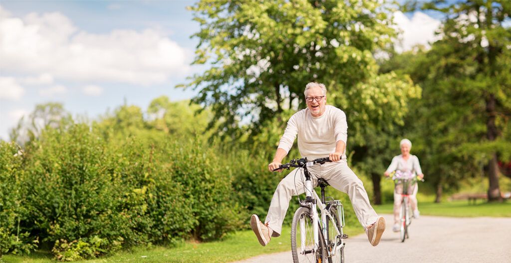 happy senior couple riding bicycles at summer park